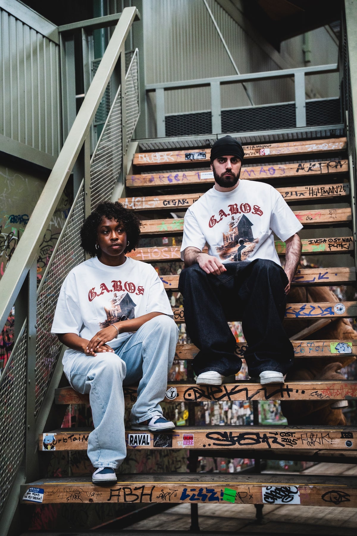 Two people wearing the white GABOS T-shirt on stairs